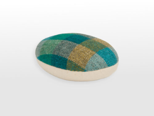 Angled view of oval ham with green checked fabric ontop and cream on the bottom